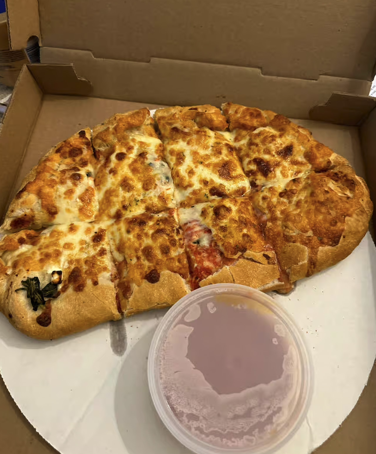 Cheese calzone in a box with a container of marinara next to it